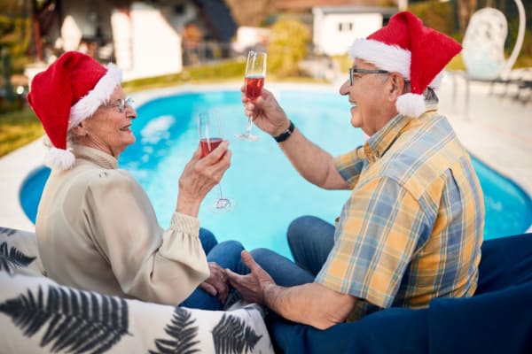 Happy mature couple in Santa hats by the pool