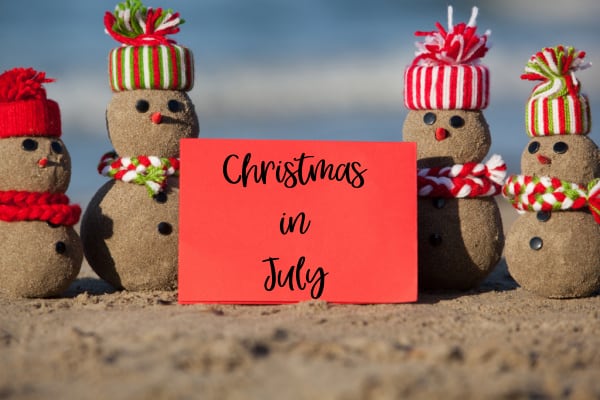 small snowman family on beach with a sign that says Christmas in July