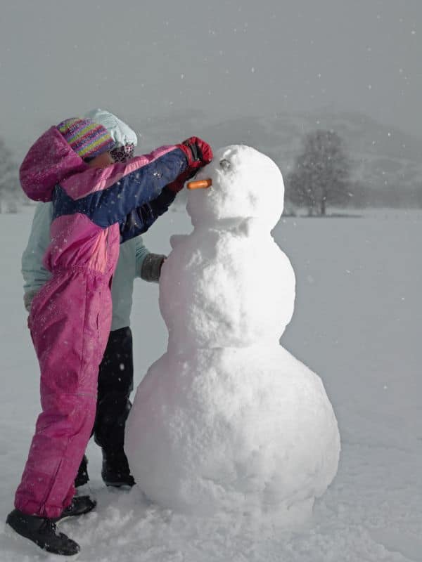 2 children building a large snowman