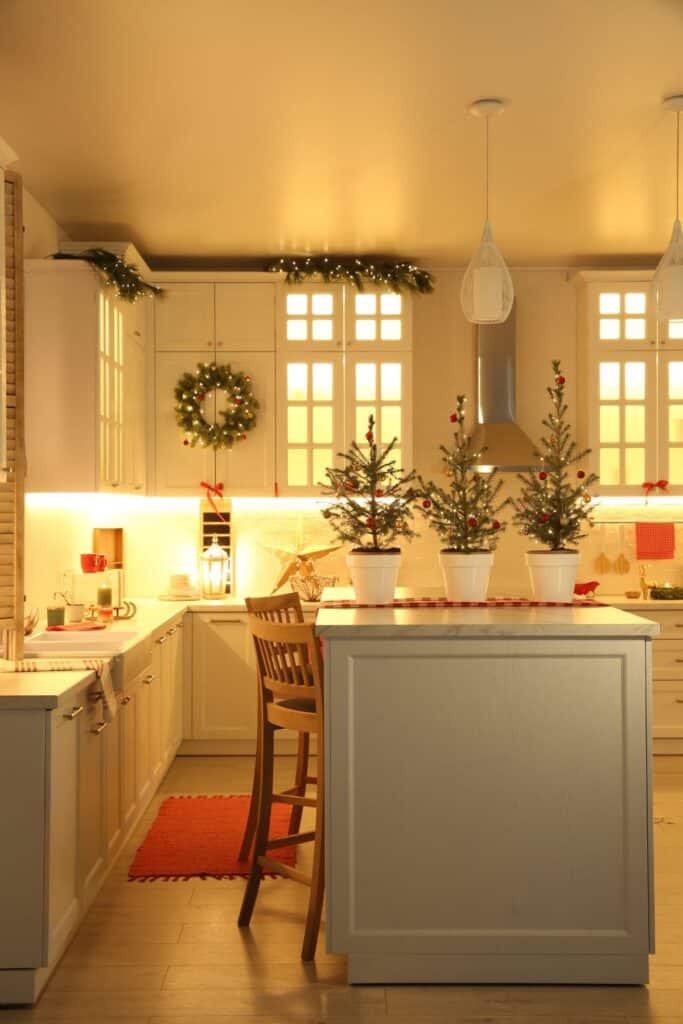 kitchen decorated for Christmas with small trees, wreaths and lights